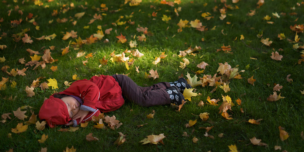 木もれ日が綺麗な落ち葉の中で眠る娘